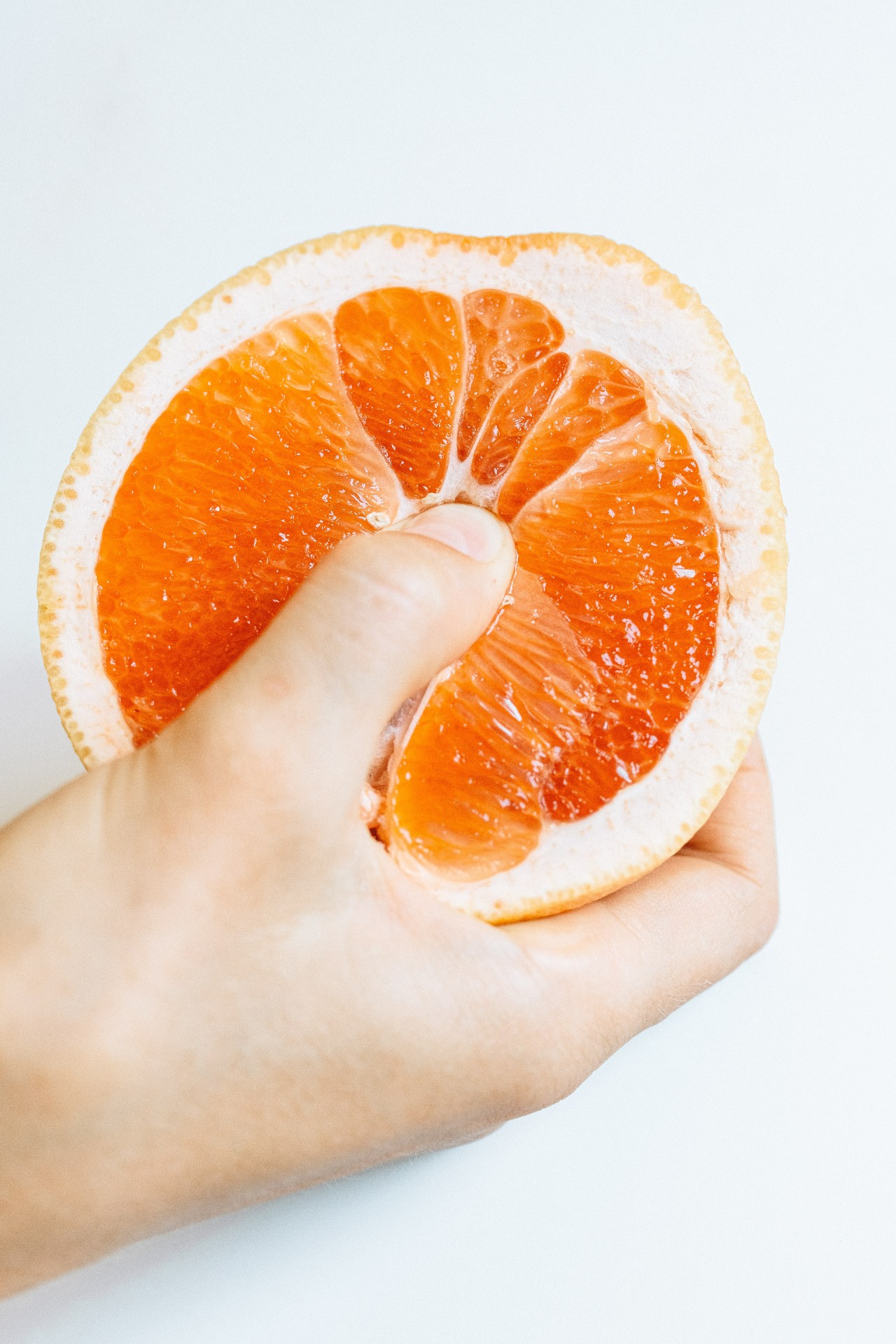 Weißer Hintergrund und in der Mitte sieht man eine Orange mit einem Daumen in der Mitte. 