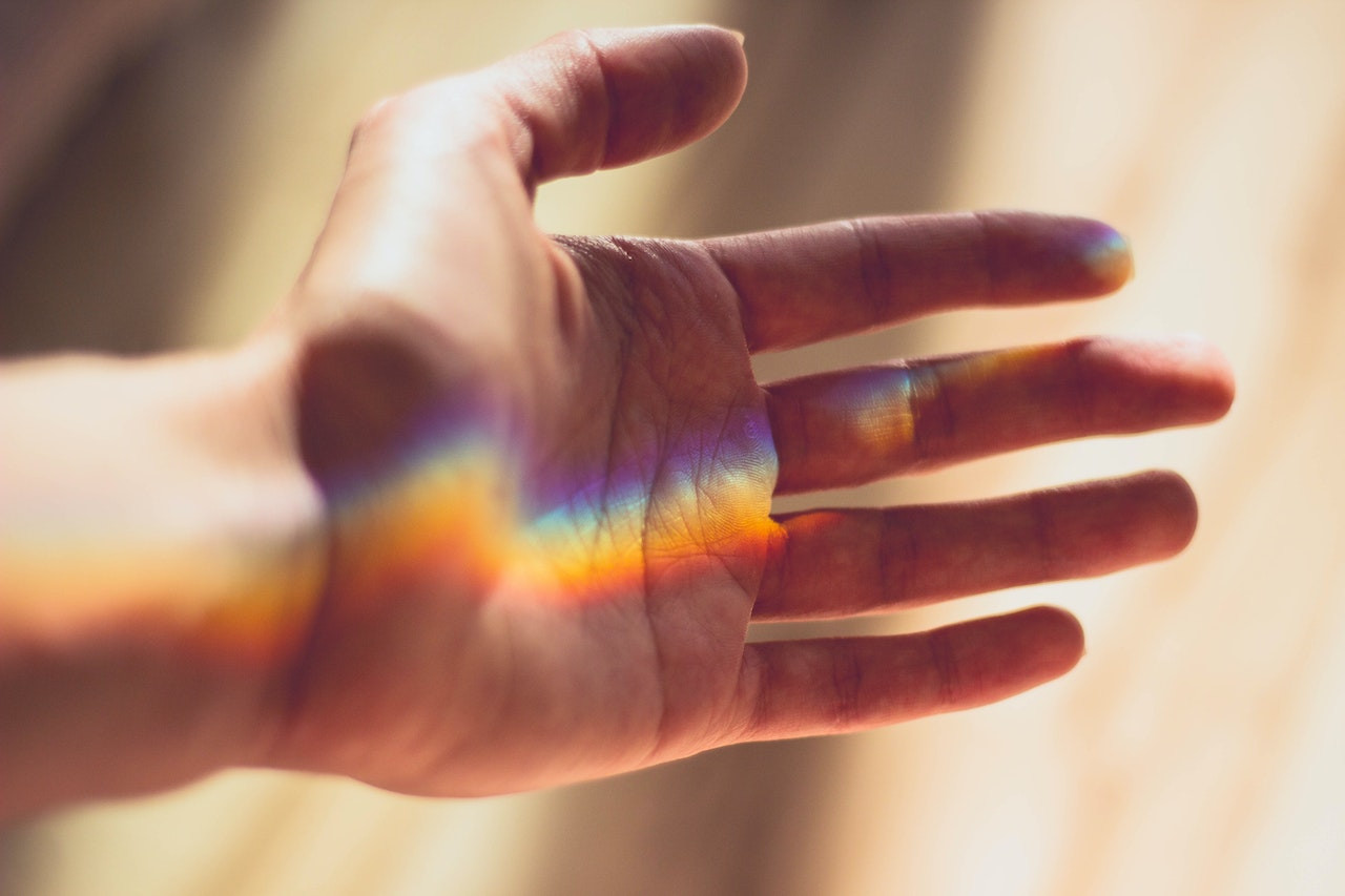 Hand mit Lichtreflexionen, die den Regenbogen zeigen