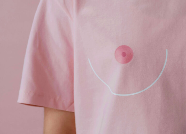 Person in pink T-shirt with a stylized breast illustration on the front.