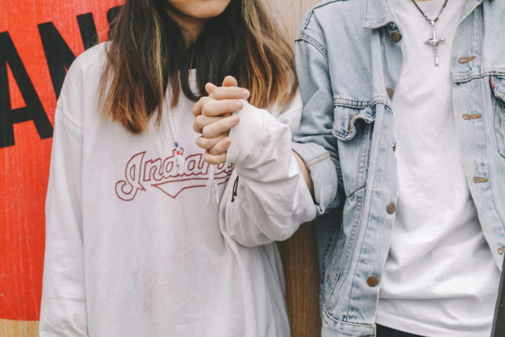 A young couple holding hands in casual attire.